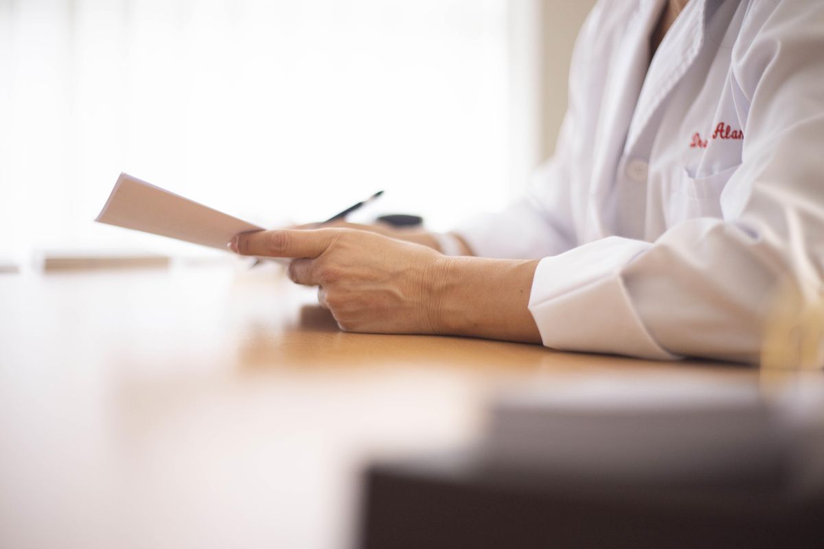 A clinician at a desk reading a printed document