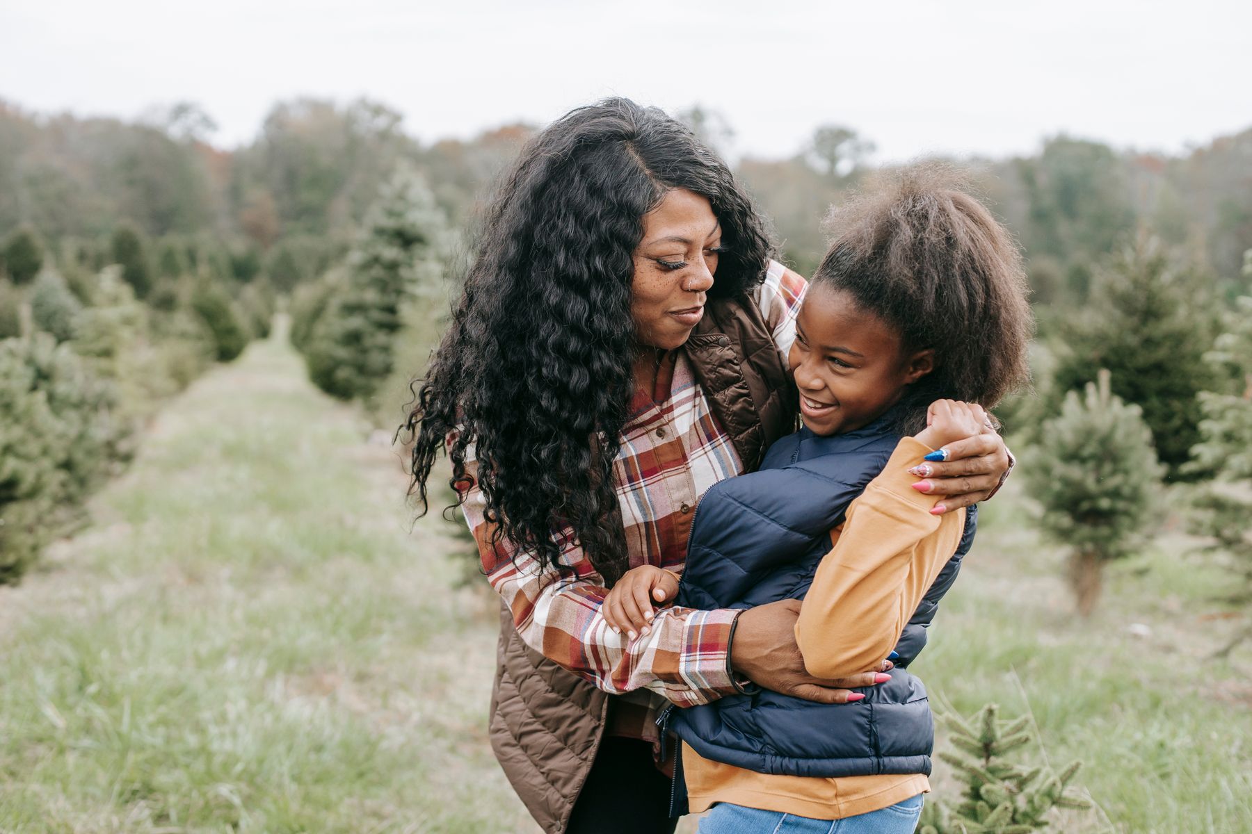 A mother hugging her smiling daughter outdoors